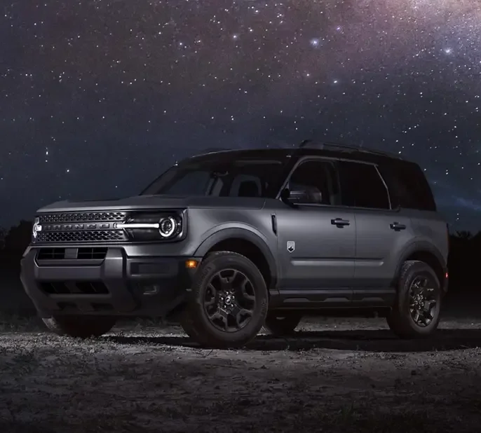 A black new Ford Bronco Sport with the Black Appearance Package is parked on a rocky shoreline next to the ocean.