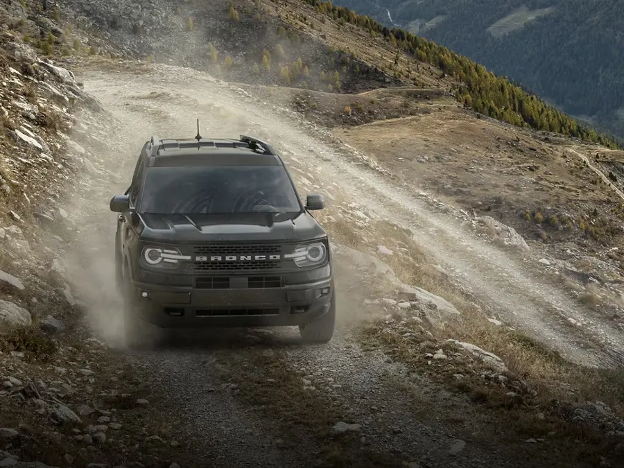 Black Ford Bronco driving on a rocky mountain trail.